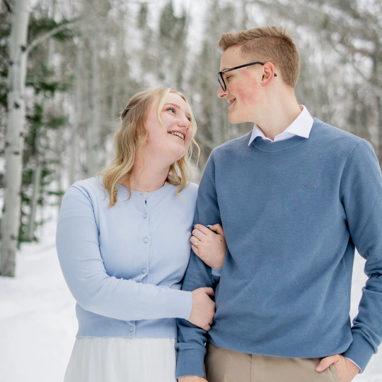 Aaron and Emily smile at each other while Emily holds Aaron's arm.